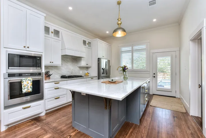 Kitchen featuring stainless steel appliances, premium range hood, a center island, white cabinets, and glass insert cabinets