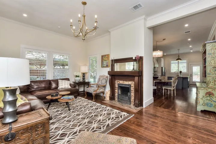 Living area featuring a chandelier, wood finished floors, crown molding, recessed lighting, and a fireplace with flush hearth