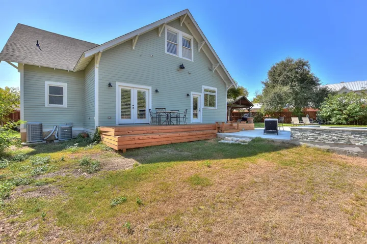 Rear view of property featuring french doors, a gazebo, a deck, roof with shingles, and a patio