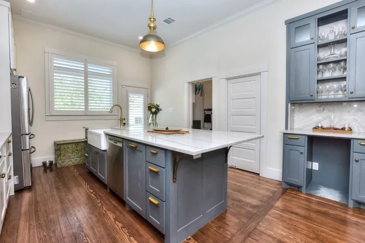 Kitchen with appliances with stainless steel finishes, crown molding, dark wood-style floors, light stone countertops, and pendant lighting