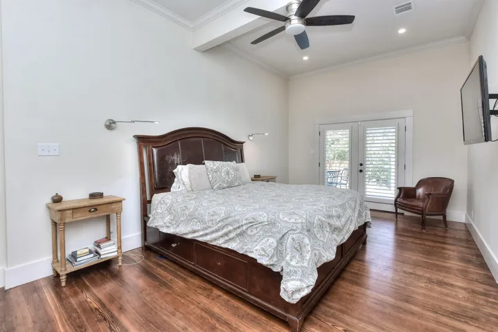 Bedroom featuring access to outside, beam ceiling, wood finished floors, french doors, and crown molding