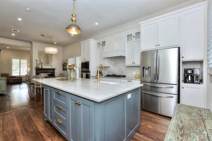 Kitchen featuring stainless steel appliances, custom exhaust hood, open floor plan, light stone countertops, and tasteful backsplash