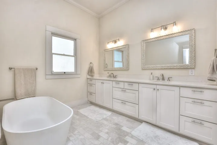 Bathroom featuring double vanity, a soaking tub, and crown molding