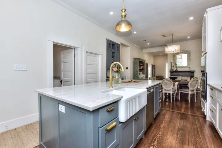 Kitchen with open floor plan, an island with sink, oven, light stone countertops, and recessed lighting