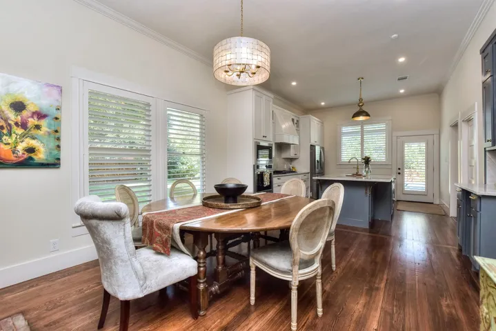 Dining space with a chandelier, dark wood-style flooring, ornamental molding, and recessed lighting
