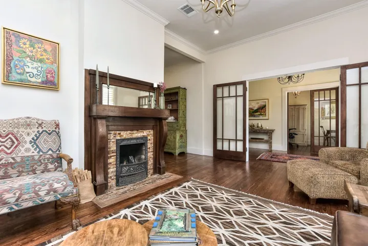 Living area featuring a chandelier, wood finished floors, crown molding, and a fireplace with flush hearth