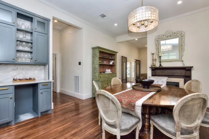 Dining room with dark wood-style floors, a bar, ornamental molding, and recessed lighting