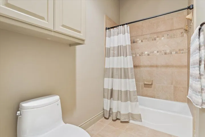 Bathroom featuring shower / tub combo with curtain and tile patterned flooring