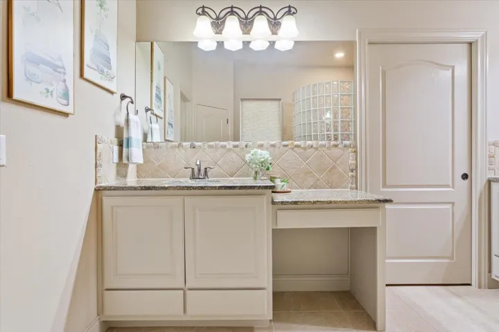 Bathroom featuring vanity, decorative backsplash, and light tile patterned floors