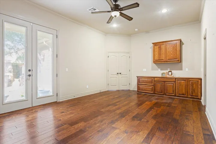 Bar featuring brown cabinets, ornamental molding, dark wood-type flooring, french doors, and recessed lighting