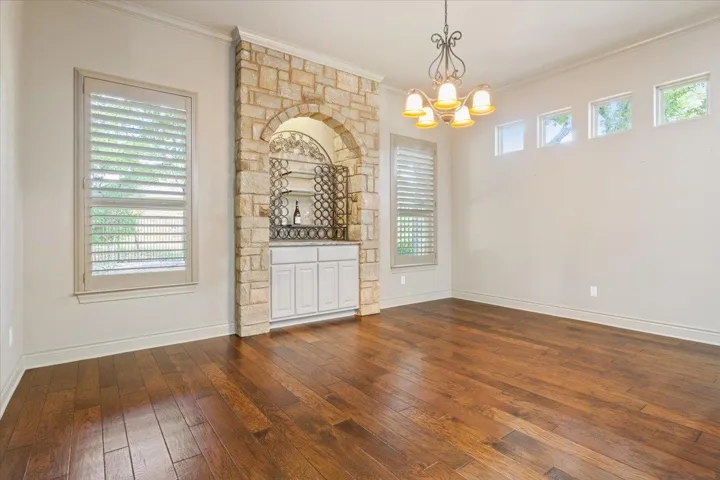 Spare room featuring dark wood-style floors, ornamental molding, and a chandelier