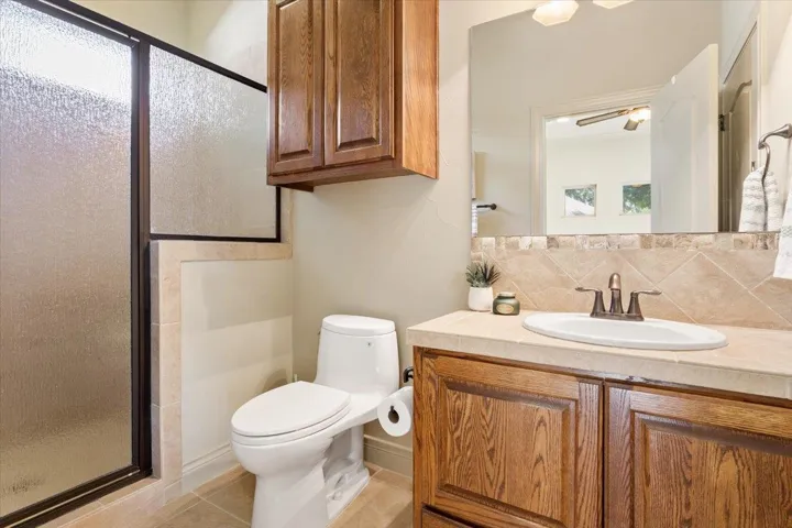 Bathroom with a shower stall, vanity, backsplash, and light tile patterned floors