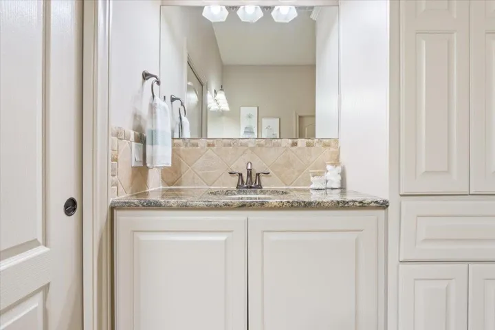 Bathroom featuring vanity and decorative backsplash