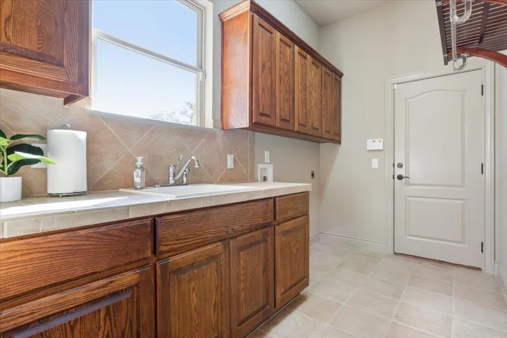 Kitchen featuring tasteful backsplash, brown cabinetry, tile countertops, and light tile patterned flooring