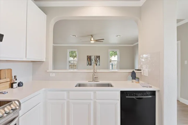 Kitchen featuring backsplash, dishwasher, and white cabinets