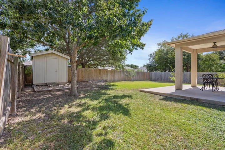 Fenced backyard featuring a shed and a patio area