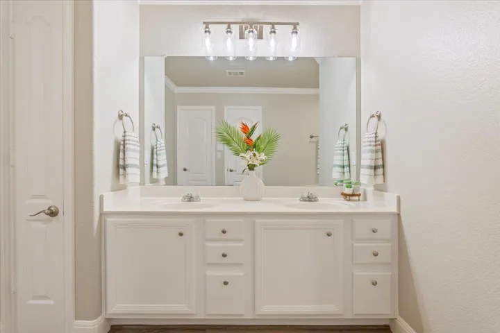 Bathroom featuring a textured wall, double vanity, and ornamental molding