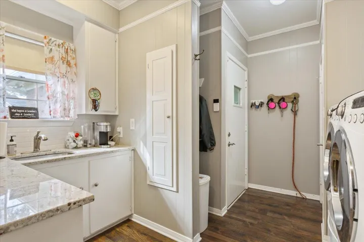 The laundry room is so much more than a laundry room.  The countertops are granite. This area includes a sink, a window over the sink, washer/dryer hookups, clothes drying hanging area, and an additional pantry.  It also features the half bath featured in the next photo....