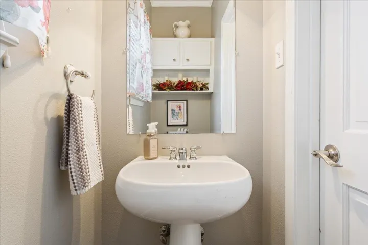 The half bathroom is in the laundry room.  It includes a pedestal sink, commode, & attached cabinet, plus a framed mirror.  The door on the right leads to the backyard as well....Perfect if you add a hot tub or pool...