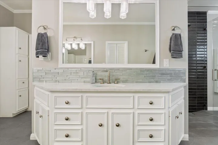 One of the two primary bathroom's vanities. Quartz counter top with tile backsplash, large framed mirror & two towel holders...