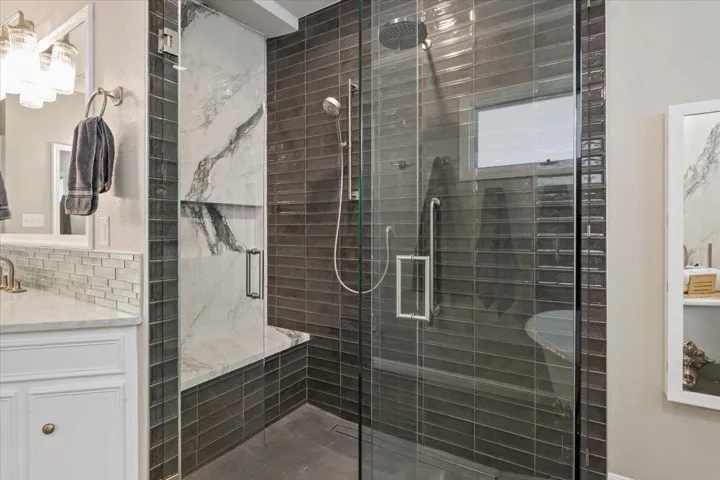 This bathroom was remodeled in July2023.  Seamless, thick glass , walk-in shower features double shower heads, a shower seat, and beautiful grey subway tile....