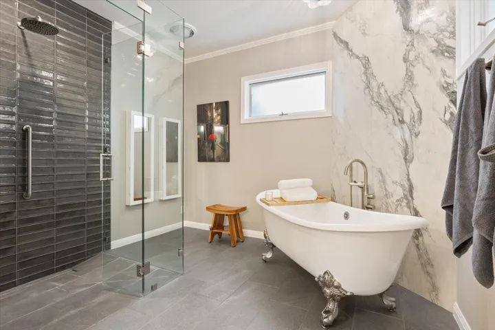 Also completely remodeled is the gorgeous primary bathroom.  Seamless glass, large walk-in shower & stunning claw foot tub with a marble tile backsplash behind it.  Muted transom window rolls out for extra ventilation and more natural light, crown molding, & 2 mirrored jewelry cabinets on the side wall...