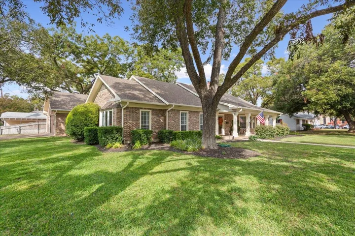 From the corner of the front yard, view your soaring pecan trees, lush lawn & side entry garage...