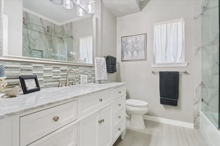 The second bathroom has also been remodeled & includes a seamless glass panel tub/shower combo.  Quartz countertops, glass tile backsplash, & framed mirror.