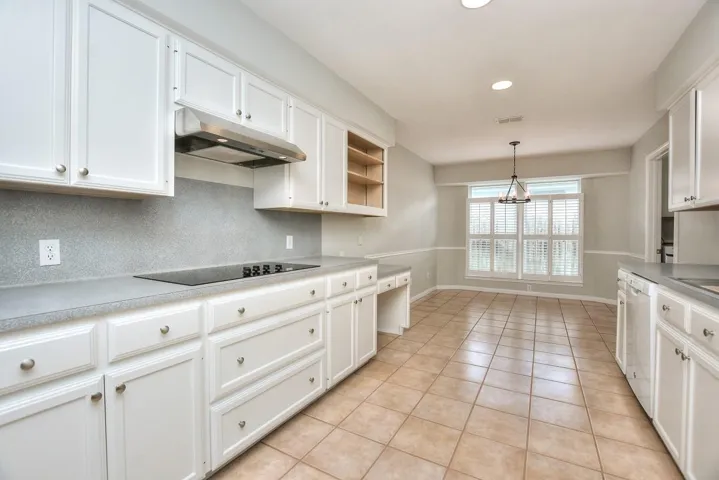 Kitchen with white cabinets, pendant lighting, light countertops, under cabinet range hood, and recessed lighting