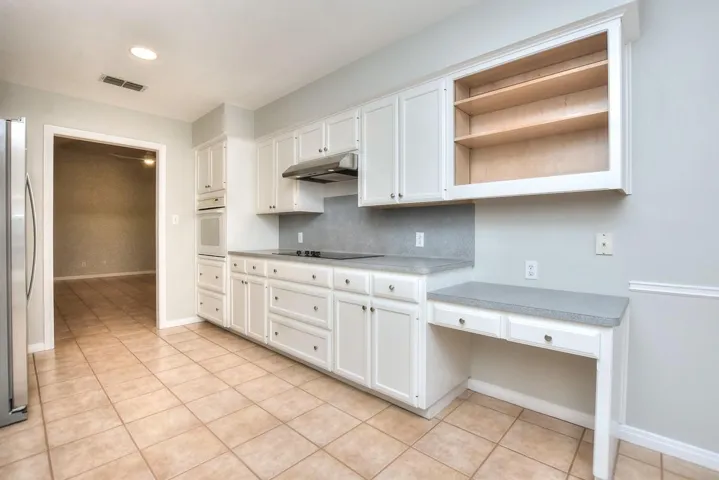 Kitchen with open shelves, white cabinets, light countertops, freestanding refrigerator, and recessed lighting