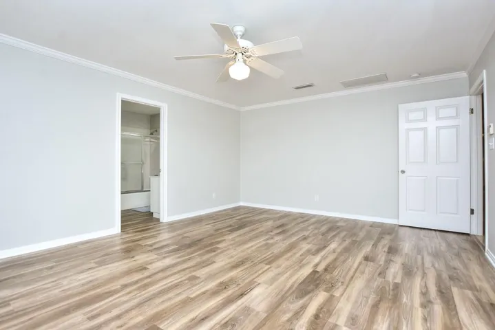 Unfurnished bedroom featuring crown molding, light wood finished floors, and ceiling fan