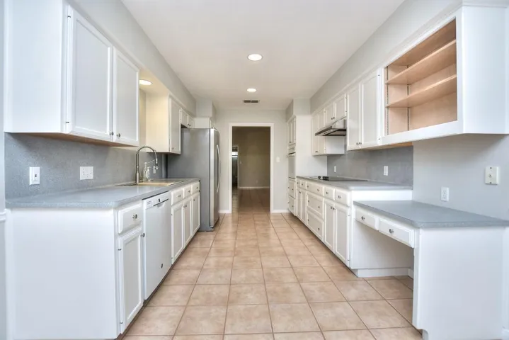 Kitchen featuring tasteful backsplash, light countertops, white cabinetry, open shelves, and recessed lighting