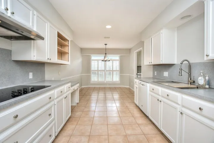 Kitchen with backsplash, white cabinets, light countertops, pendant lighting, and recessed lighting