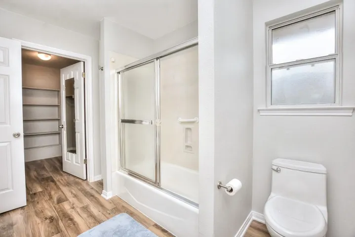 Full bathroom with light wood-style flooring and shower / bath combination with glass door
