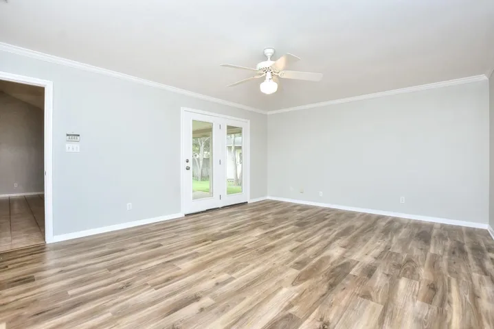 Spare room featuring light wood-type flooring, a ceiling fan, and ornamental molding
