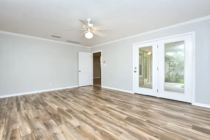 Empty room featuring crown molding, light wood finished floors, and ceiling fan