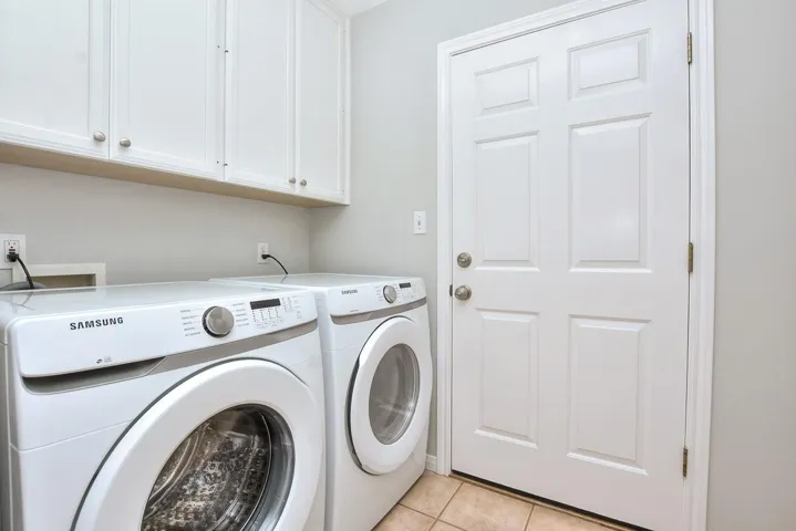 Laundry room featuring light tile patterned floors, separate washer and dryer, and cabinet space