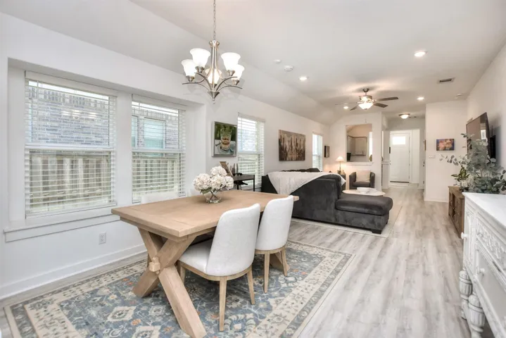 Dining room with baseboards, vaulted ceiling, recessed lighting, light wood finished floors, and ceiling fan with notable chandelier