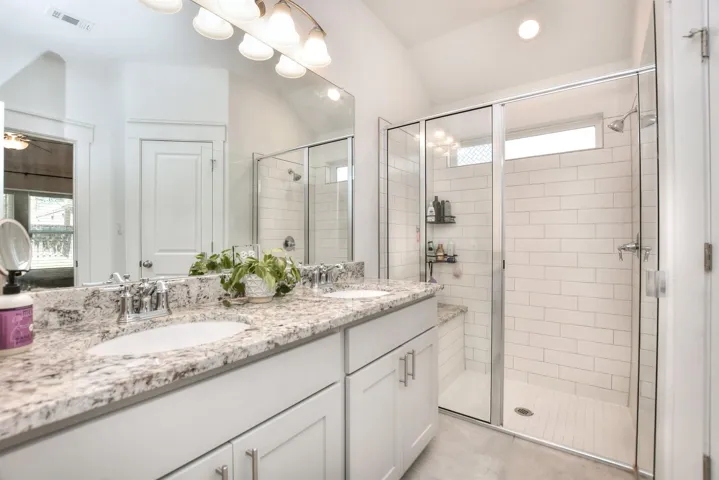 Bathroom with a sink, visible vents, a shower stall, and double vanity