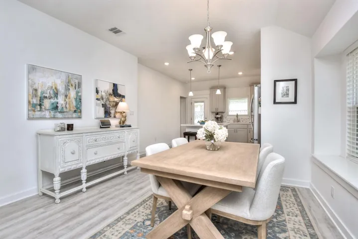 Dining area featuring light wood-style flooring, baseboards, a notable chandelier, and visible vents