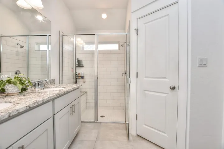 Full bathroom featuring a sink, tile patterned flooring, double vanity, and a stall shower