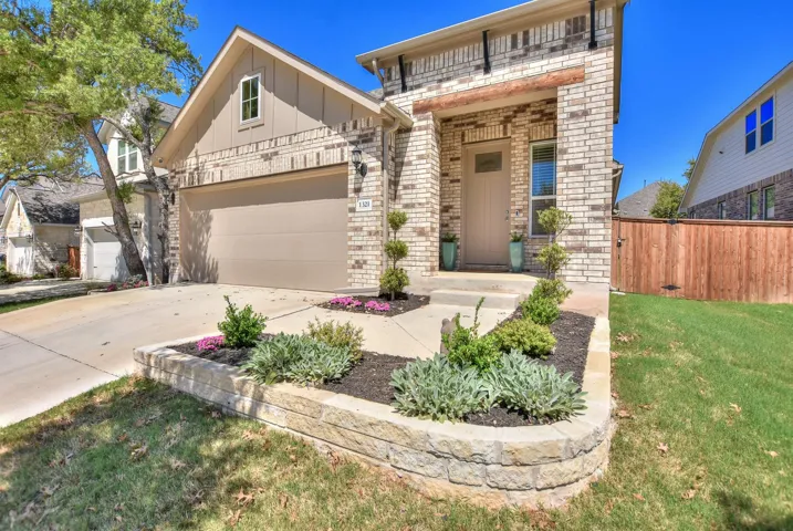 View of front facade featuring board and batten siding, a front yard, fence, brick siding, and driveway