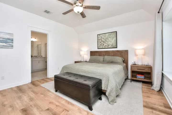 Bedroom featuring visible vents, baseboards, light wood finished floors, and lofted ceiling