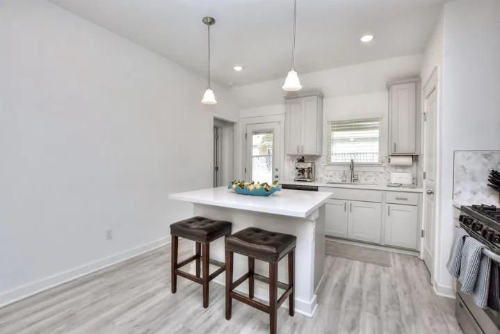 Kitchen with a kitchen breakfast bar, range, light countertops, backsplash, and a sink
