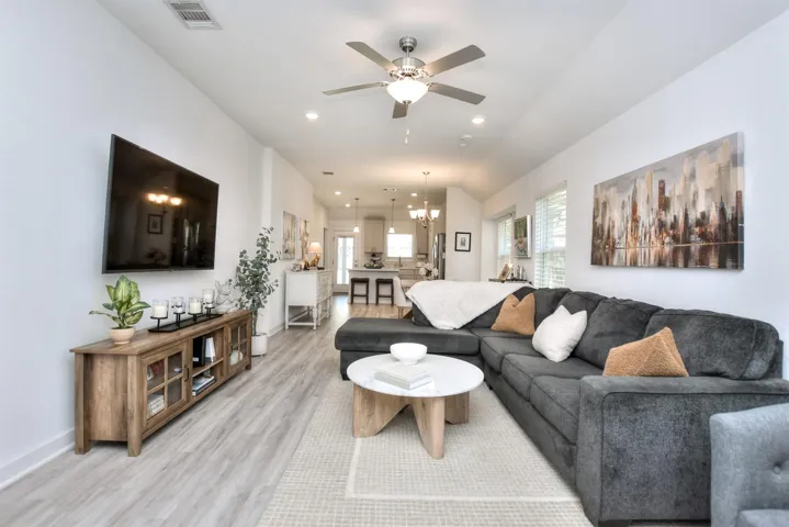 Living room featuring ceiling fan with notable chandelier, light wood-type flooring, visible vents, recessed lighting, and baseboards