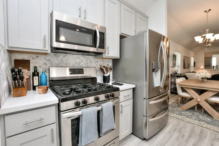 Kitchen featuring light countertops, stainless steel appliances, open floor plan, decorative backsplash, and a notable chandelier