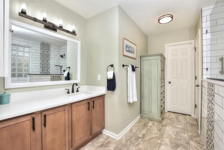 A large white framed mirror & an updated light fixture, faucet, towel racks & pulls all updated & freshly painted.