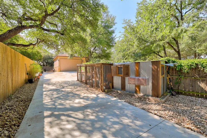 View of chicken coop, raised garden beds along fenceline and oversized shop/garage