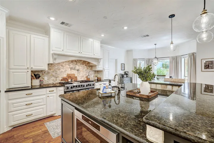 Kitchen with backsplash, light wood-type flooring, white cabinetry, and recessed lighting