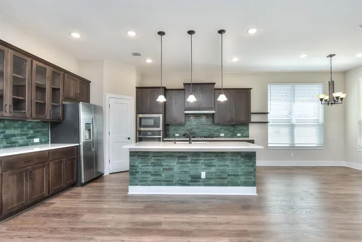 Kitchen featuring LVP flooring cabinets, glass fronted cabinets, stainless steel appliances, and upgraded lighting